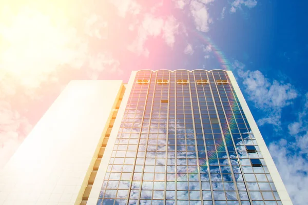 Un rascacielos con muchas ventanas contra un hermoso cielo azul. Concepto empresarial y financiero . — Foto de Stock