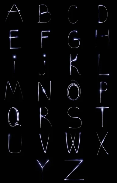 Alfabeto feito de luz de néon sobre um fundo preto. Vista superior isolada . — Fotografia de Stock
