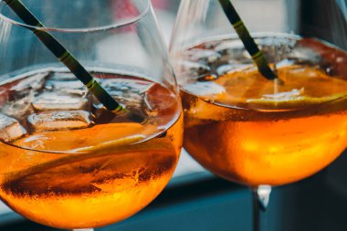 Bardakta buz küpleri ve çevre dostu karton tüplü Aperol alkollü içecek. Popüler kokteyl, bar menüsü, portakal suyu..