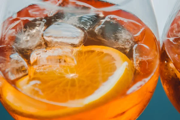 Aperol alcoholic drink with ice cubes in a glass and an eco-friendly cardboard tube. Popular cocktail, bar menu, orange liquid.