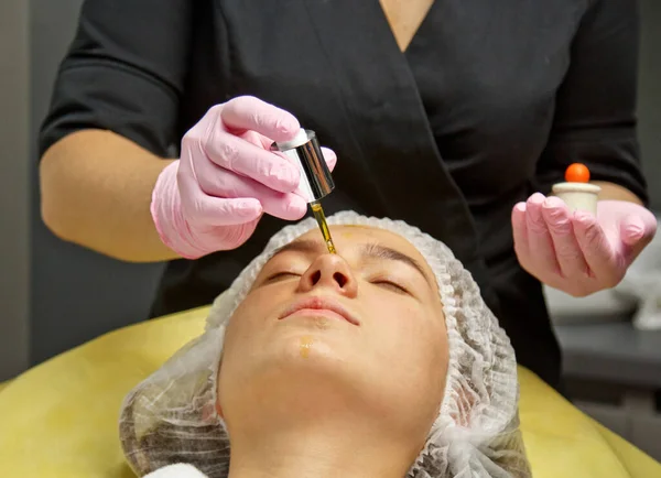 Preparação para procedimentos no escritório do cosmetologista. aplicação de óleo para hidratar o rosto com uma pipeta especial . — Fotografia de Stock