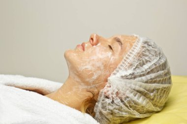 konsept güzellik. Bir kozmetolojistin elleri bir kadının yüzüne krem koyar. Güzellik kızı yüzüne bir krem uygular.