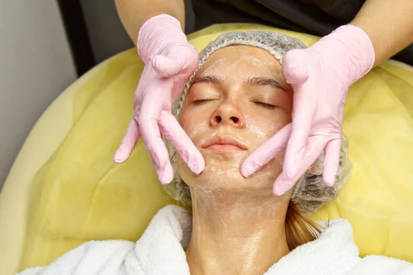 Koncepce. Ruce kosmetologa položila na tvář ženy krém. Beauticijník aplikuje na tvář dívky krém. — Stock fotografie