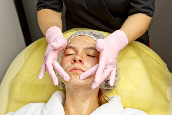 Koncepcja kosmetyczka. Ręce kosmetologa umieścić krem na twarzy kobiety. Kosmetyczka nakłada krem na twarz dziewczyny. — Zdjęcie stockowe