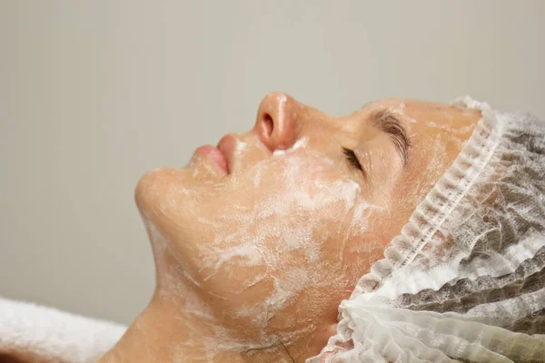 Koncepce. Ruce kosmetologa položila na tvář ženy krém. Beauticijník aplikuje na tvář dívky krém. — Stock fotografie
