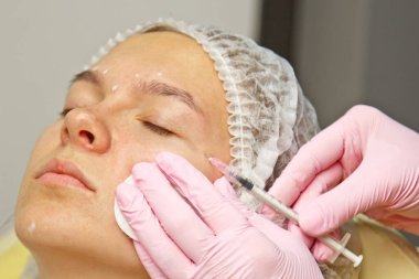 kontur plastik. Bir Kozmetolog sıkın ve bir kadın yüzü cilt kırışıklıkları pürüzsüz bir botulinum toksin enjekte.