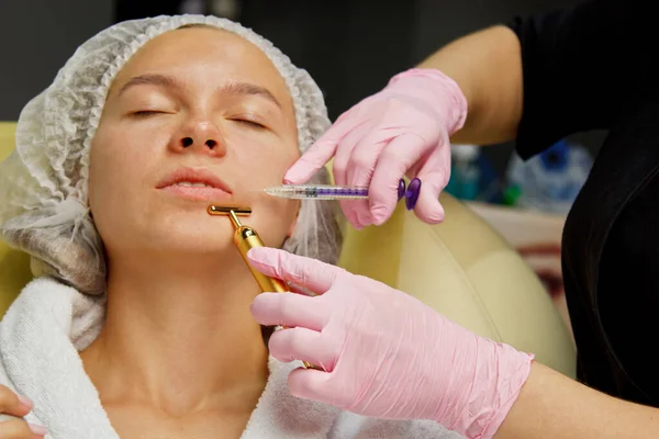 Z tworzywa sztucznego. Kosmetolog wstrzykuje toksyny botulinowej, aby dokręcić i wygładzić zmarszczki na skórze kobiecej twarzy. — Zdjęcie stockowe