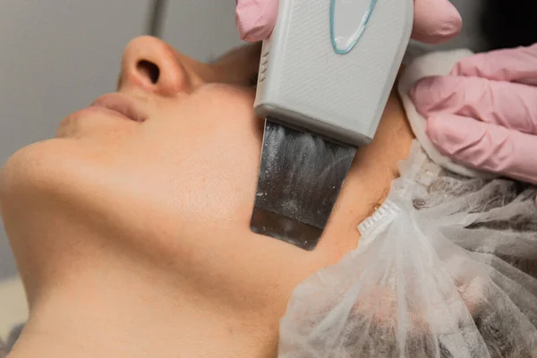 Närbild. Ultraljud ansiktsrengöring. Modern utrustning. Kosmetolog gör kosmetisk förfarande på kvinnan ansikte. — Stockfoto