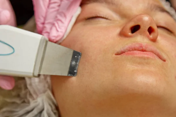 close-up. Ultrasonic face cleaning. Modern equipment. Beautician does cosmetic procedure on woman face.