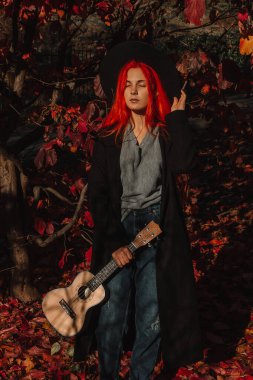 Uzun saçlı seksi kızıl kız ukulele çalıyor. Mükemmel bir kadın portresi. Muhteşem güçlü ve kalın saçlar. Koyu mavi gözler. Doğal güzellik, temiz ten, yüz ve saç bakımı.