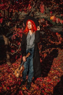 Uzun saçlı seksi kızıl kız ukulele çalıyor. Mükemmel bir kadın portresi. Muhteşem güçlü ve kalın saçlar. Koyu mavi gözler. Doğal güzellik, temiz ten, yüz ve saç bakımı.