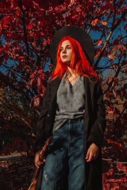 Uzun saçlı, seksi, kızıl saçlı kız. Sarı yapraklı arka planda mükemmel bir kadın portresi. Muhteşem saçlar ve koyu mavi gözler. Doğal güzellik, temiz ten, yüz ve saç bakımı.