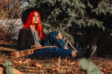 Uzun saçlı seksi kızıl kız ukulele çalıyor. Mükemmel bir kadın portresi. Muhteşem güçlü ve kalın saçlar. Koyu mavi gözler. Doğal güzellik, temiz ten, yüz ve saç bakımı.