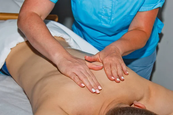 Wellness-Konzept. Ein professioneller Masseur gönnt einem Mann im Wellnessbereich eine Thai-Massage mit Bambusstäben. Entspannung und Erholung nach der Arbeit. — Stockfoto