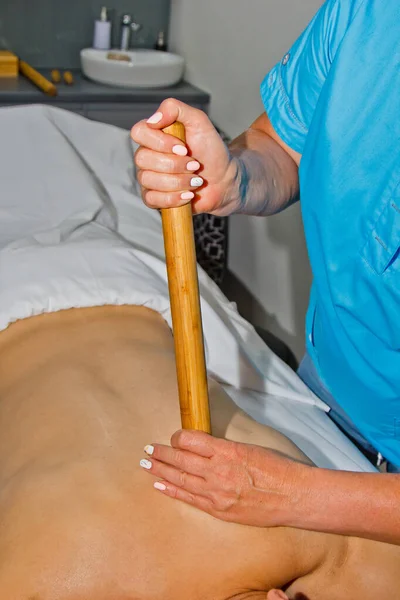 Koncepcja wellness. Profesjonalny masażysta robi facetowi tajski masaż bambusowymi pałeczkami w spa. Relaks i regeneracja po pracy. — Zdjęcie stockowe