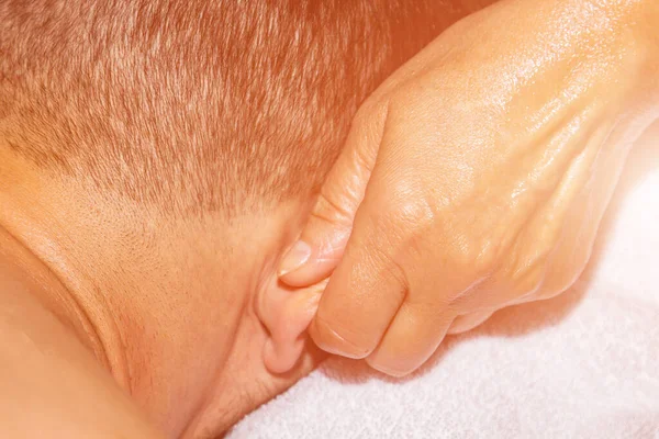 Massothérapeute professionnelle féminine fait massage thérapeutique des oreilles avec les mains d'un athlète masculin. femme massages un homme — Photo