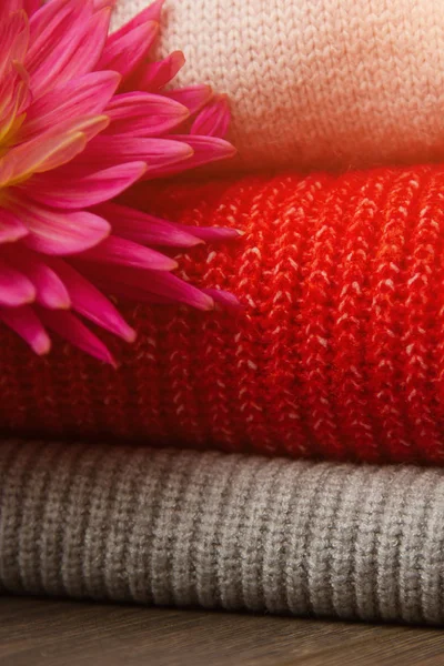 Patroon van kleurrijke gebreide truien close-up. Handgemaakte merino wol product. Een stapel gevouwen kleren met bloemen. — Stockfoto