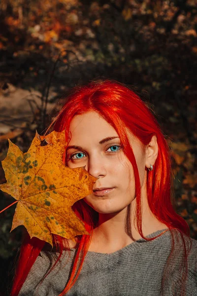 Sexy beautiful redhead girl with long, strong and thick hair. Perfect woman portrait on a background of autumn foliage. Gorgeous deep blue eyes. Natural beauty, clean skin, face and hair care.