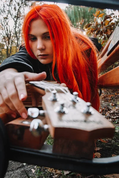 Κοκκινομάλλα με μακριά μαλλιά παίζει με το γιουκαλίλι στο πάρκο. Σχολείο, μουσική παιδεία, ο μαθητής μαθαίνει να παίζει έγχορδο. Χέρια ενός μουσικού, κλασική, μελωδία, δημιουργικότητα. — Φωτογραφία Αρχείου