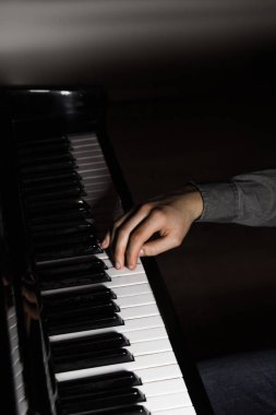 Piyanoda bir erkek el. Avuç içi tuşların üzerinde yer alır ve müzik okulunda klavyeli enstrüman çalar. öğrenci oynamayı öğrenir. eller piyanist. siyah koyu arka plan.