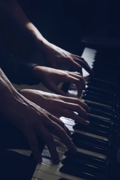Spielt vier männliche Hände auf dem Klavier. Palmen liegen auf den Tasten und spielen das Tasteninstrument in einer Musikschule. Schüler lernt spielen. Hände eines Pianisten. schwarzer dunkler Hintergrund. — Stockfoto