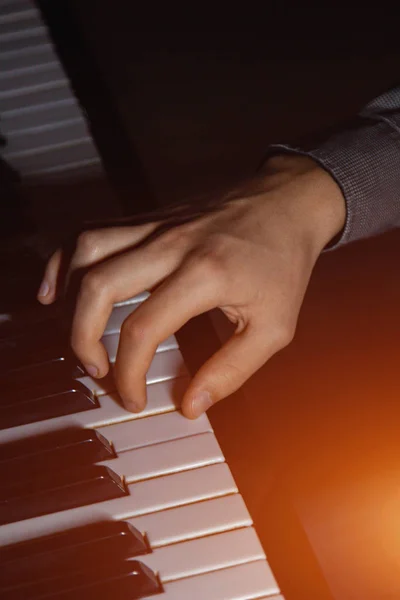 Une main masculine sur le piano. La paume repose sur les touches et joue de l'instrument à clavier dans l'école de musique. élève apprend à jouer. pianiste des mains. fond noir foncé . — Photo