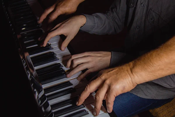 Négy férfikéz zongorázik. tenyér fekszik a billentyűket, és játszani a billentyűzet eszköz egy zeneiskolában. A diák megtanul játszani. egy zongorista keze. fekete sötét háttér. — Stock Fotó