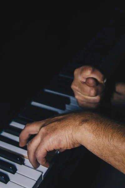 Dos manos masculinas en el piano. las palmas yacen en las teclas y tocan el instrumento de teclado en la escuela de música. estudiante aprende a jugar. manos pianista. fondo negro oscuro . — Foto de Stock