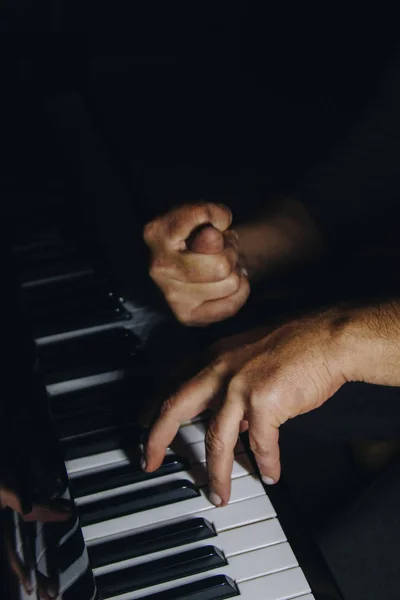 Dos manos masculinas en el piano. las palmas yacen en las teclas y tocan el instrumento de teclado en la escuela de música. estudiante aprende a jugar. manos pianista. fondo negro oscuro . — Foto de Stock