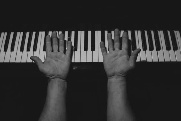 Vier männliche Hände am Klavier. Auf einem Keyboard in einer Musikschule drehten sich die Handflächen um. Schüler lernt spielen. Hände eines Pianisten. schwarzer dunkler Hintergrund. — Stockfoto