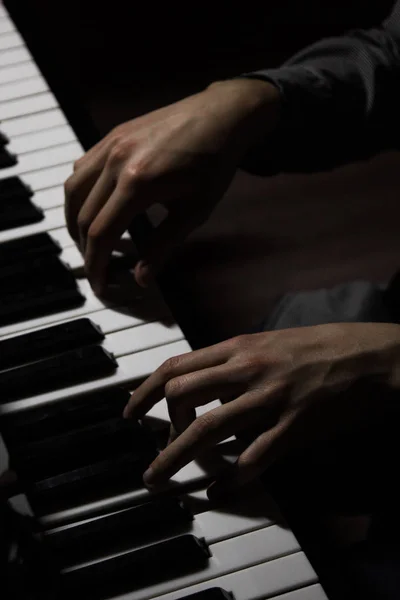 Deux mains masculines sur le piano. palms se trouvent sur les touches et jouent de l'instrument à clavier dans l'école de musique. élève apprend à jouer. pianiste des mains. fond noir foncé . — Photo