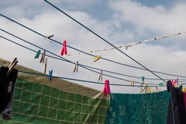 Çamaşır ipinde bir mandal asılı. Çamaşırların yıkandığı gün temiz çarşaflar ve açık havada giyilen bir ip. Yeşil doğa ve gökyüzünün arka planına karşı.