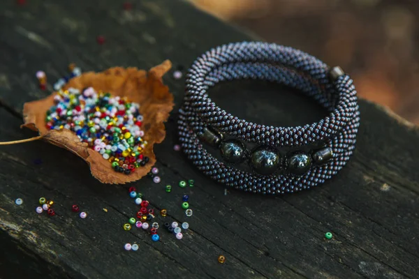 Mooie, glanzende, kleur armband met grote kralen. Op een speciale stand voor juwelen. Kralen zijn verspreid over een houten tafel. — Stockfoto