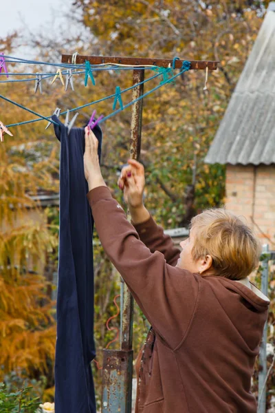 Wasserij vrouw hangt schone natte doek op wasdroger na het wassen thuis. Huishoudelijke taken en huishouding. — Stockfoto