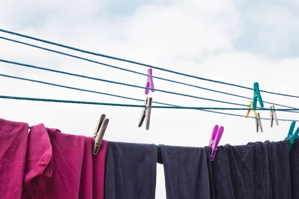 Er hangt een wasknijper aan de waslijn. Een touw met schoon linnen en kleding buiten op de dag van de wasserij. Tegen de achtergrond van groene natuur en lucht. — Stockfoto