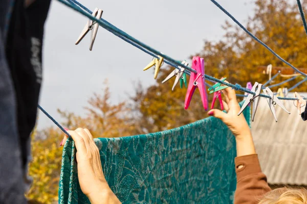 Wasserij vrouw hangt schone natte doek op wasdroger na het wassen thuis. Huishoudelijke taken en huishouding. — Stockfoto