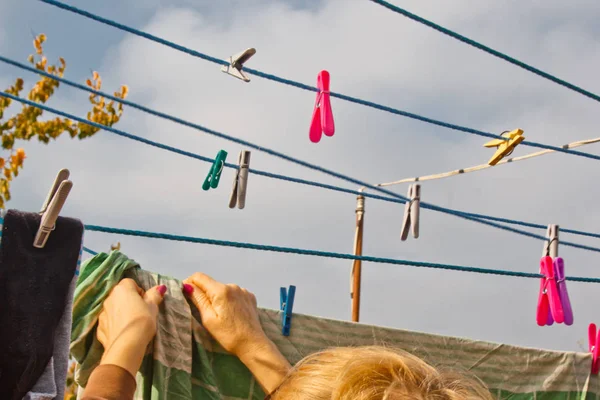 Wasserij vrouw hangt schone natte doek op wasdroger na het wassen thuis. Huishoudelijke taken en huishouding. — Stockfoto