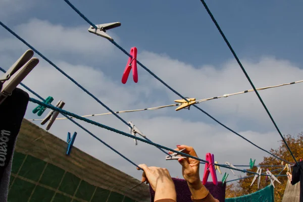 Er hangt een wasknijper aan de waslijn. Een touw met schoon linnen en kleding buiten op de dag van de wasserij. Tegen de achtergrond van groene natuur en lucht. — Stockfoto