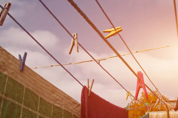 A clothespin hangs on the washing line. A rope with clean linen and clothes outdoors on the day of the laundry. Against the background of green nature and sky.