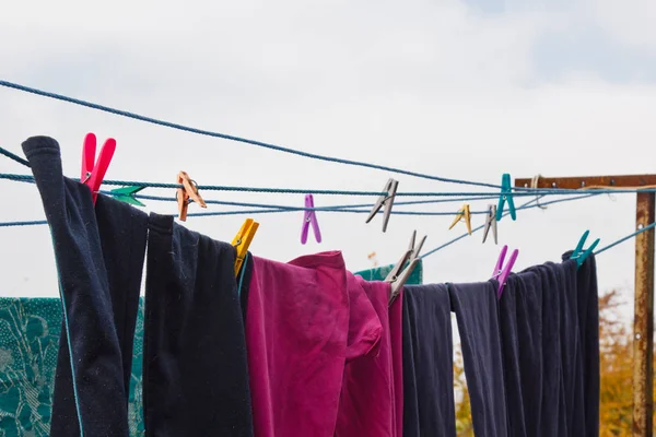 洗濯ラインには布のピンがかかっている。洗濯の日にきれいなリネンと服を屋外でロープ。緑と空を背景に. — ストック写真