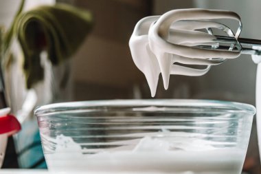 Pişirme konsepti. Cam bir kasede mükemmel doruklar için çırpılmış yumurta beyazı, mermer beyaz bir masada mikser. Kurabiye tarifi.