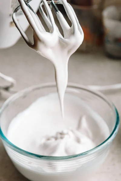 Conceptul de copt. Cremă de albușuri de ou pentru vârfuri perfecte într-un castron de sticlă, cu un mixer pe o masă albă de marmură. Reteta de cookie-uri Meringue . — Fotografie, imagine de stoc