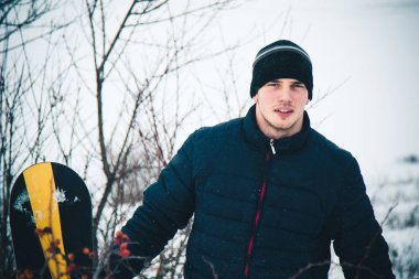 Snowboard yapan mutlu genç adam karlı dağlarda güneşli havanın tadını çıkarıyor. Kış sporu ve eğlence, açık hava aktiviteleri..