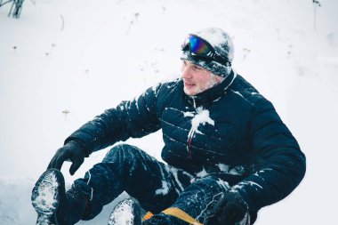 Snowboard yapan mutlu genç adam karlı dağlarda güneşli havanın tadını çıkarıyor. Kış sporu ve eğlence, açık hava aktiviteleri..