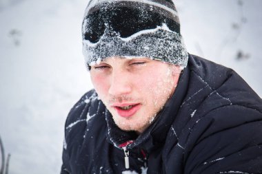 Snowboard yapan mutlu genç adam karlı dağlarda güneşli havanın tadını çıkarıyor. Kış sporu ve eğlence, açık hava aktiviteleri..