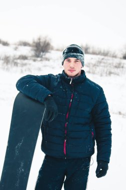 Snowboard yapan mutlu genç adam karlı dağlarda güneşli havanın tadını çıkarıyor. Kış sporu ve eğlence, açık hava aktiviteleri..