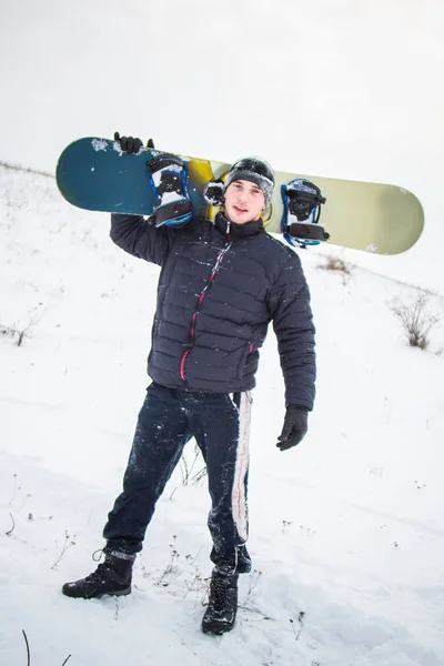 Joyeux jeune homme avec snowboard profitant d'un temps ensoleillé dans les montagnes enneigées. Sports d'hiver et loisirs, loisirs activités de plein air . — Photo