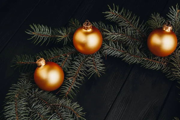 Navidad o Año Nuevo juguetes decoraciones bolas de oro y rama de árbol de piel rústico sobre fondo de madera, vista superior, espacio de copia . — Foto de Stock