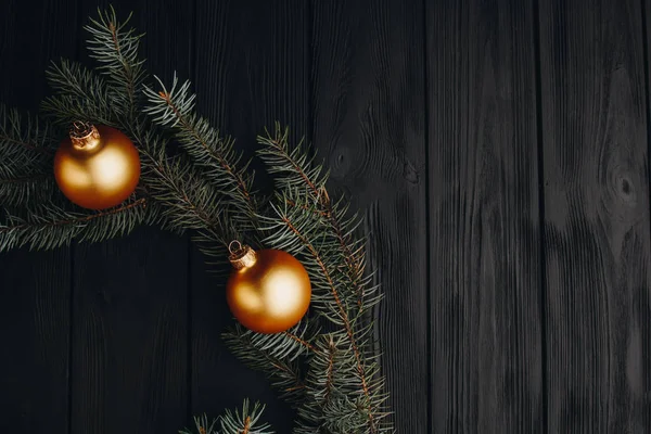 Navidad o Año Nuevo juguetes decoraciones bolas de oro y rama de árbol de piel rústico sobre fondo de madera, vista superior, espacio de copia . — Foto de Stock