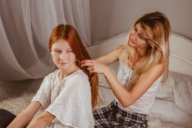 Mutlu bir aile. Gülümseyen bir anne sabah yatağında uyuduktan sonra kızının saçını örer. Anne kızını okula götürüyor. Etkileşim, temas, aşk.